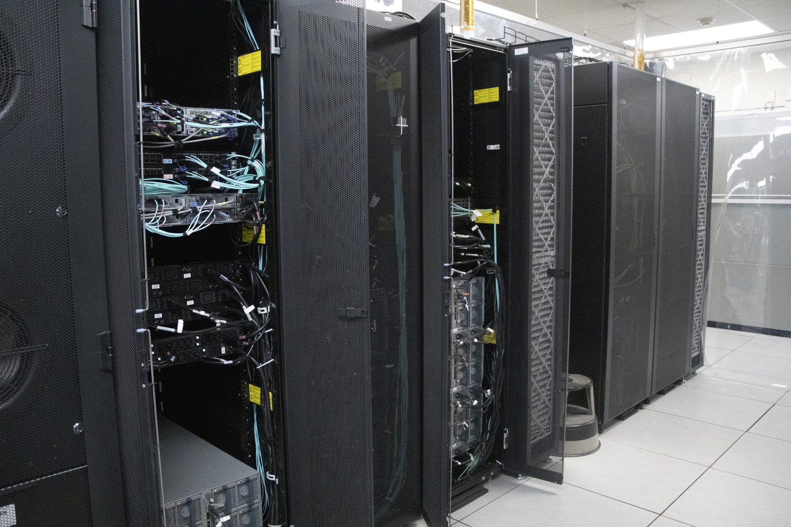 Open server racks reveal cable connections and computing equipment.